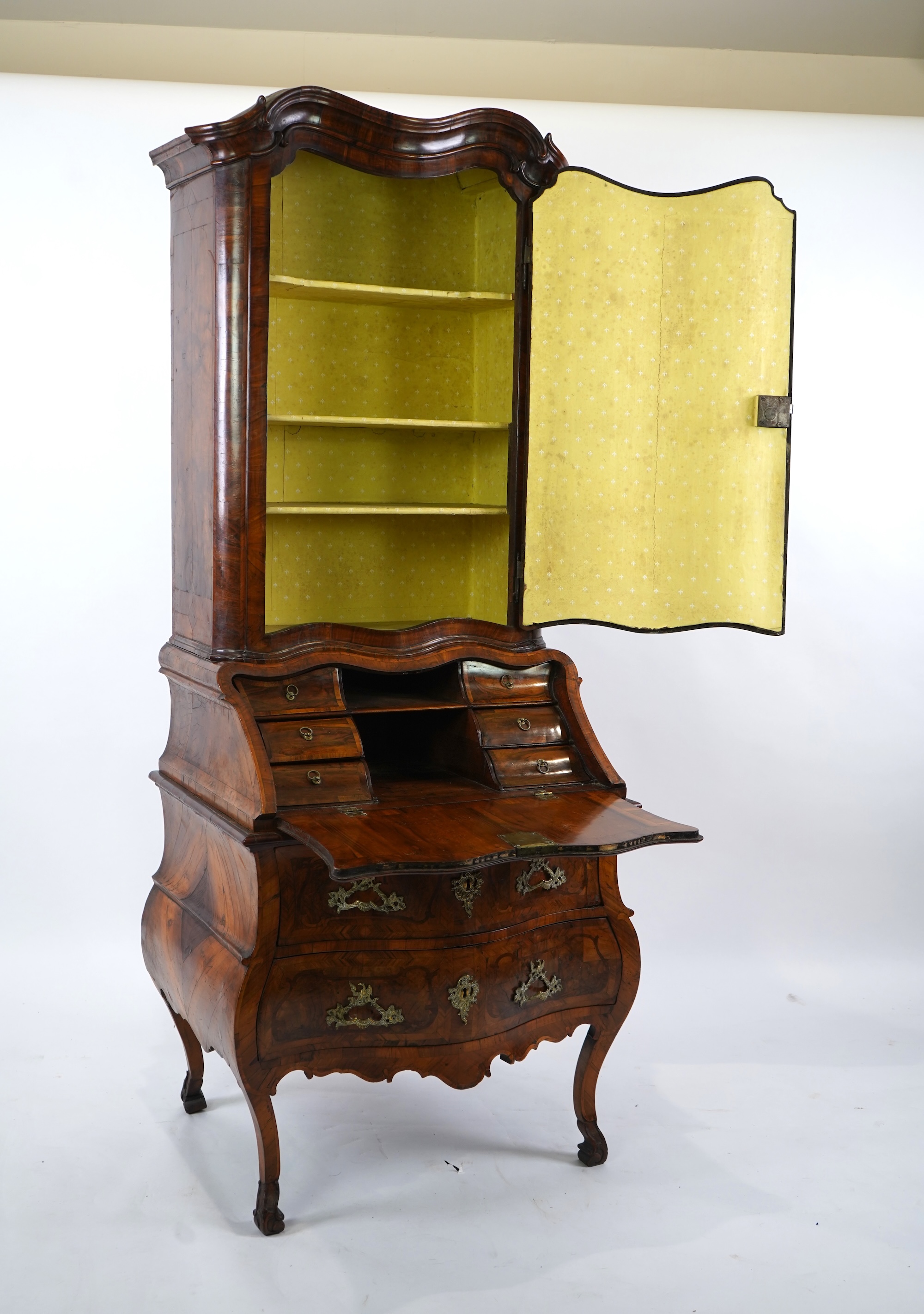 A mid 18th century North Italian or Maltese walnut and olive wood gilt metal mounted serpentine bureau cabinet